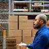 Employé rangeant des cartons sur une étagère d’entrepôt